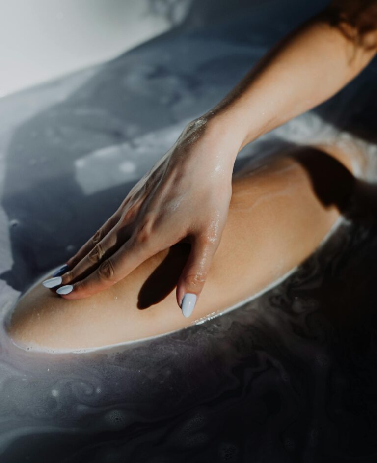 Kobieta relaksuje się w domowej przestrzeni, zamyka oczy, praktykuje uważność zmysłową i odpoczynek, odzyskując kontakt z ciałem i zmysłami